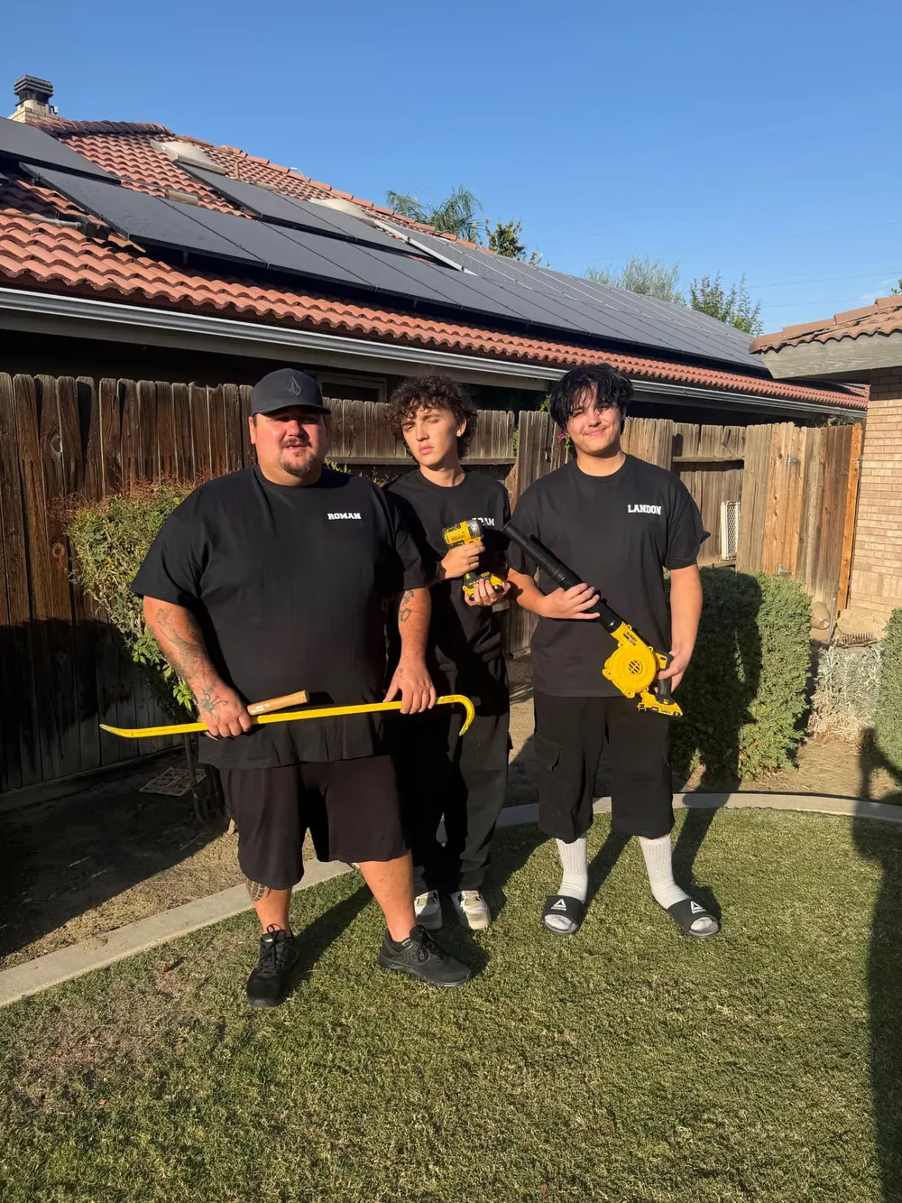 Suds and Studs team members Roman, Adam, and Landon holding tools in front of a solar-paneled Bakersfield home