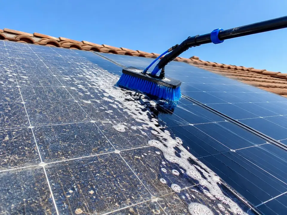 Water-fed soft brush washing dust off residential solar panels on a tile roof